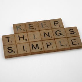 Scrabble tiles spell out "KEEP THINGS SIMPLE" on a white background. Wooden tiles with black letters and numbers suggest clarity and simplicity.