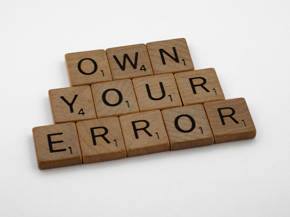 Wooden Scrabble tiles spelling "OWN YOUR ERROR" on a white background, conveying a message of accountability.