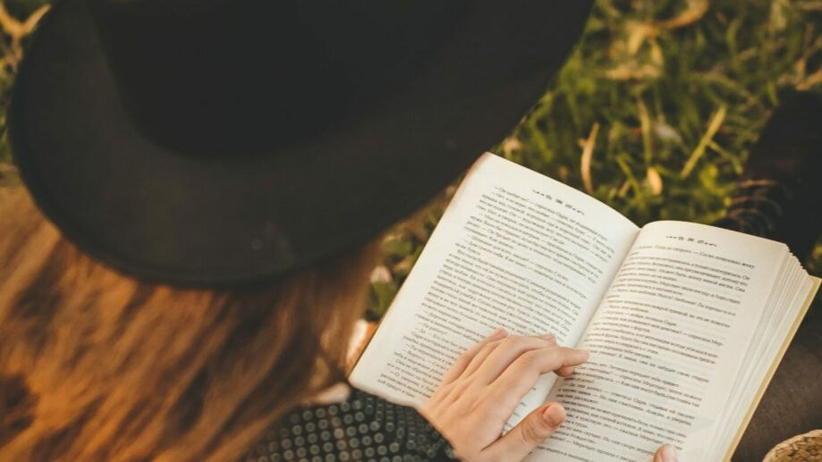 person reading book wearing dark academia outfit black hat - light and dark academia outfits