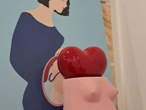 Scultura rosa a forma di corpo in gravidanza con un cuore rosso sul ventre, simbolo del percorso sulla paura del parto con la psicologa perinatale Angela Maria Nitti a Bari.