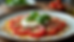 Vue rapprochée d'une assiette de carpaccio de tomates avec burrata, taralli et basilic