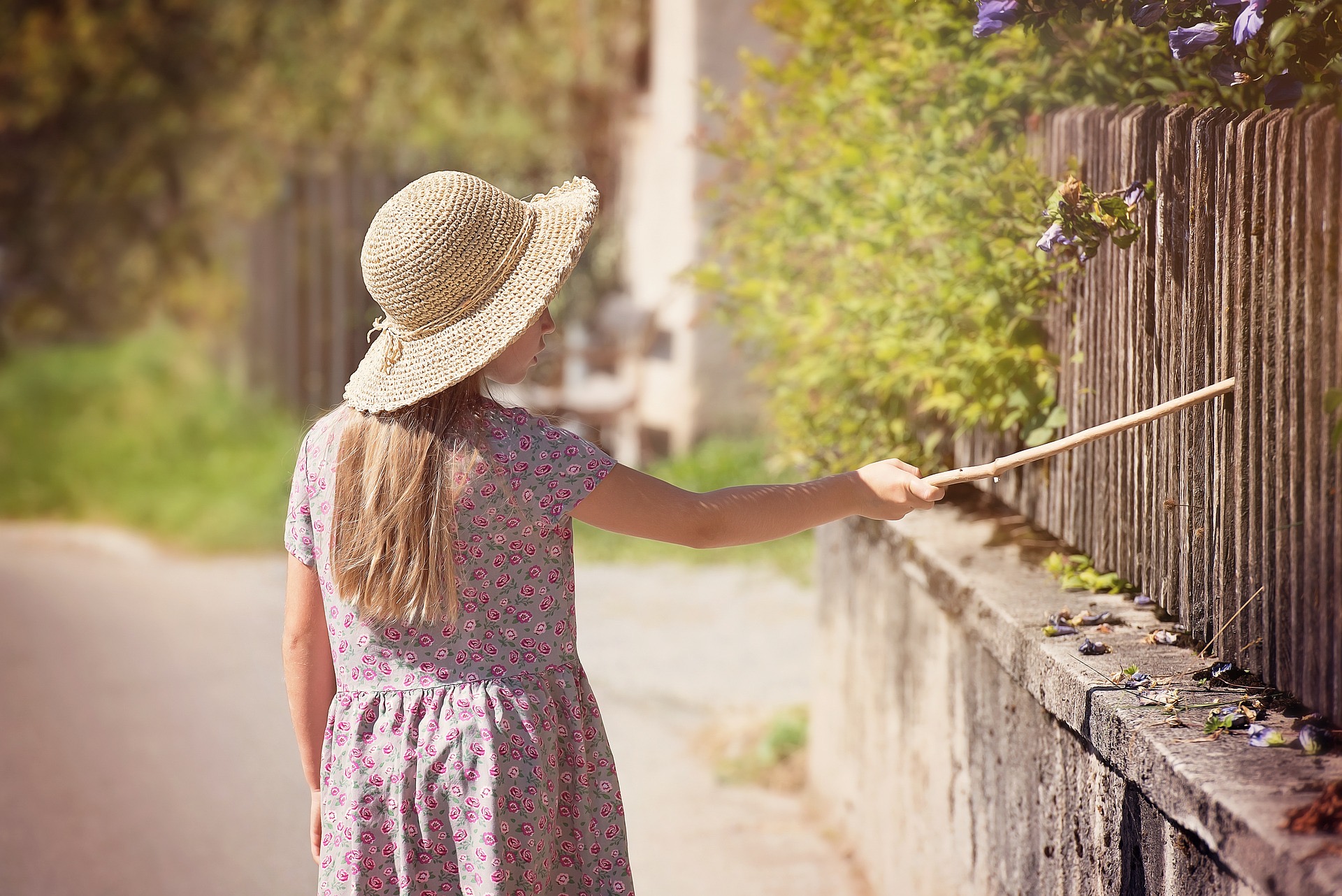 girl walking along a high fence 