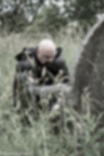 Matt Whitfield In black medieval armour, kneeling reverentially at a grave.