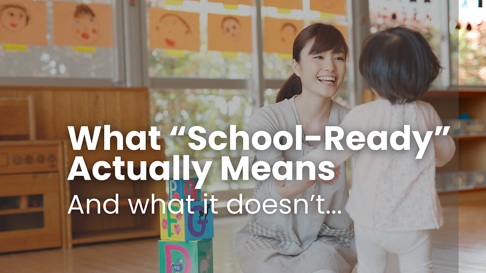 Teacher smiling at a child in a classroom with colorful blocks and drawings. Text: What “School-Ready” Actually Means And what it doesn’t…