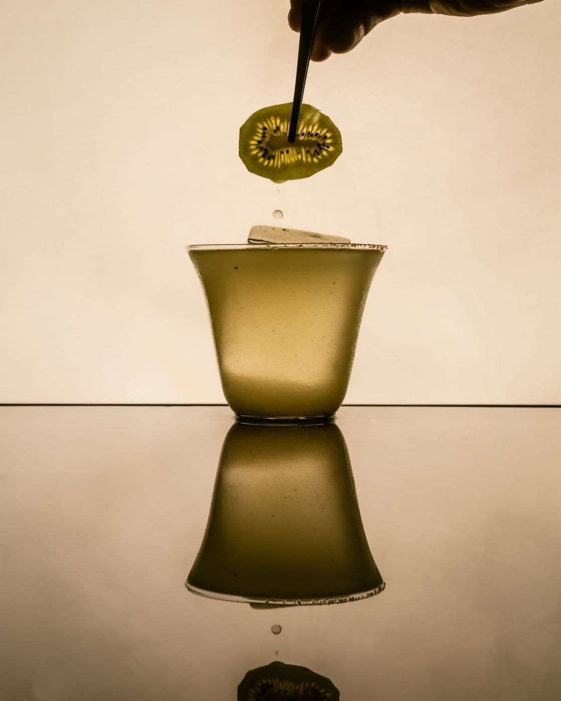 Kiwi slice dropping into a cup