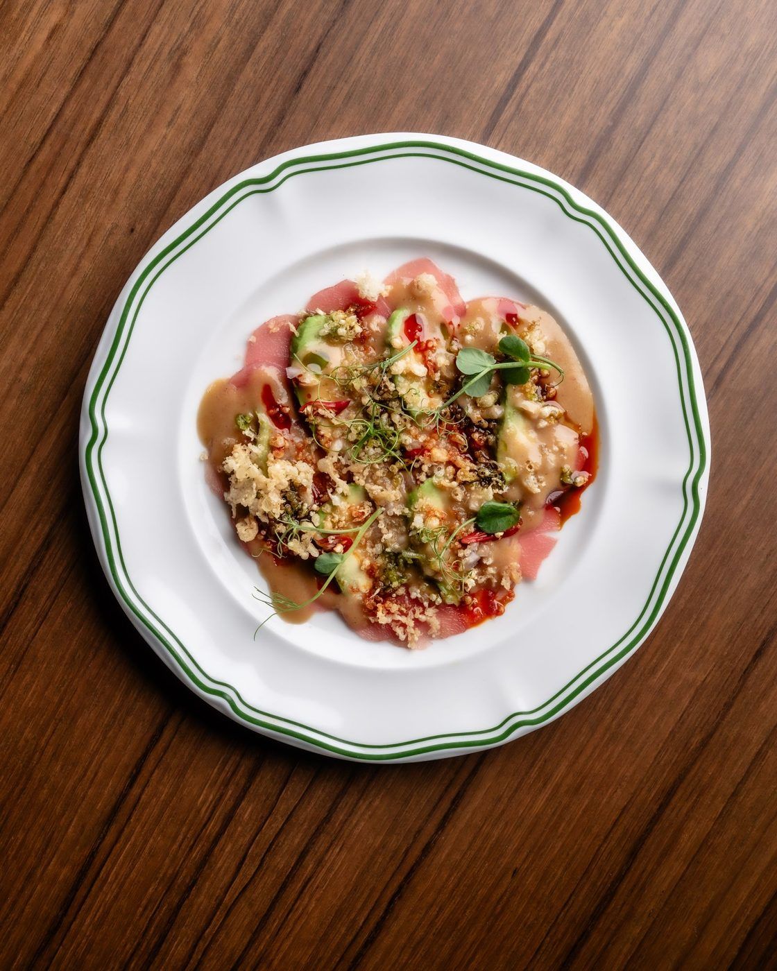 Tuna crudo on a green-rimmed plate