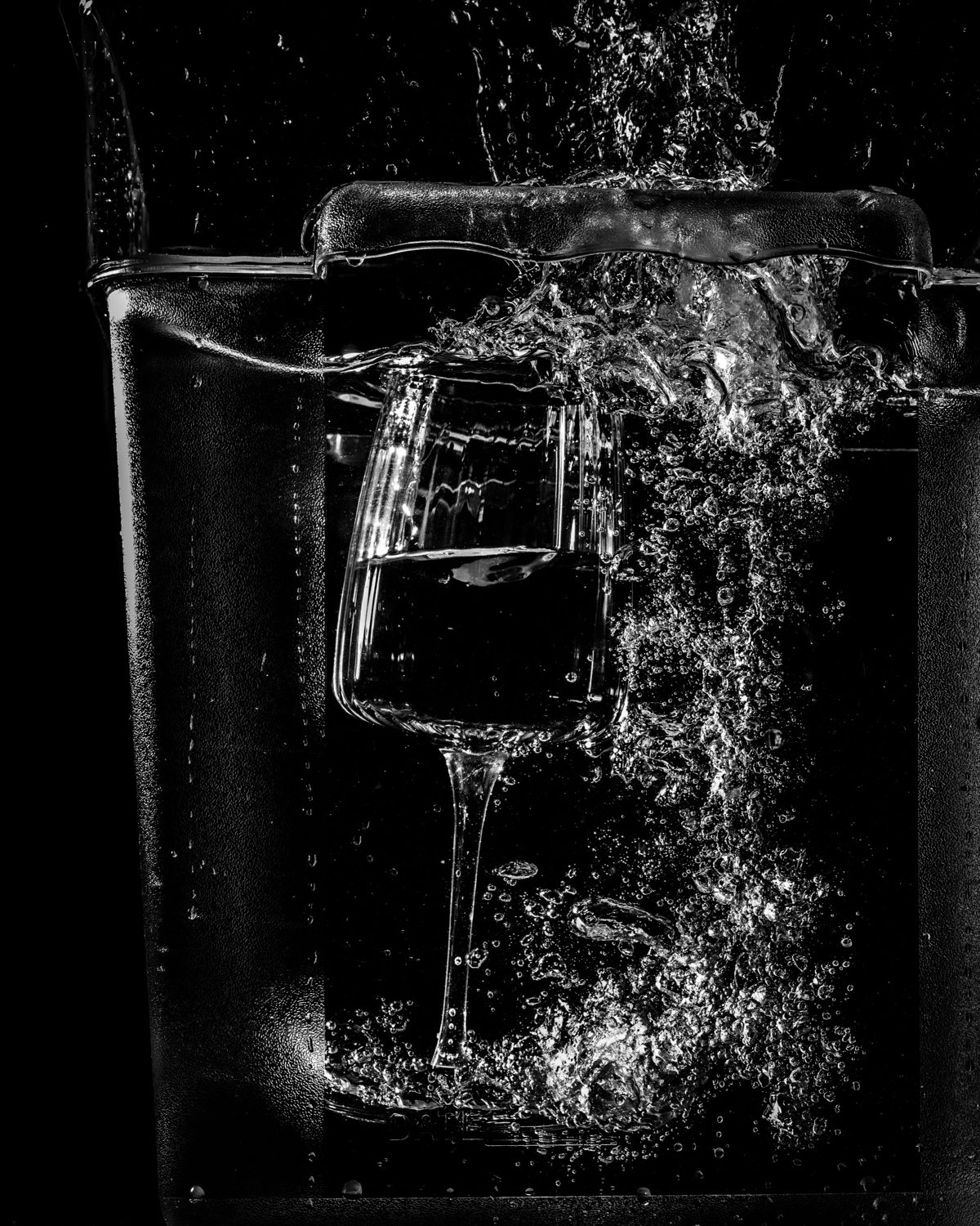 A glass plunged underwater, in black and white