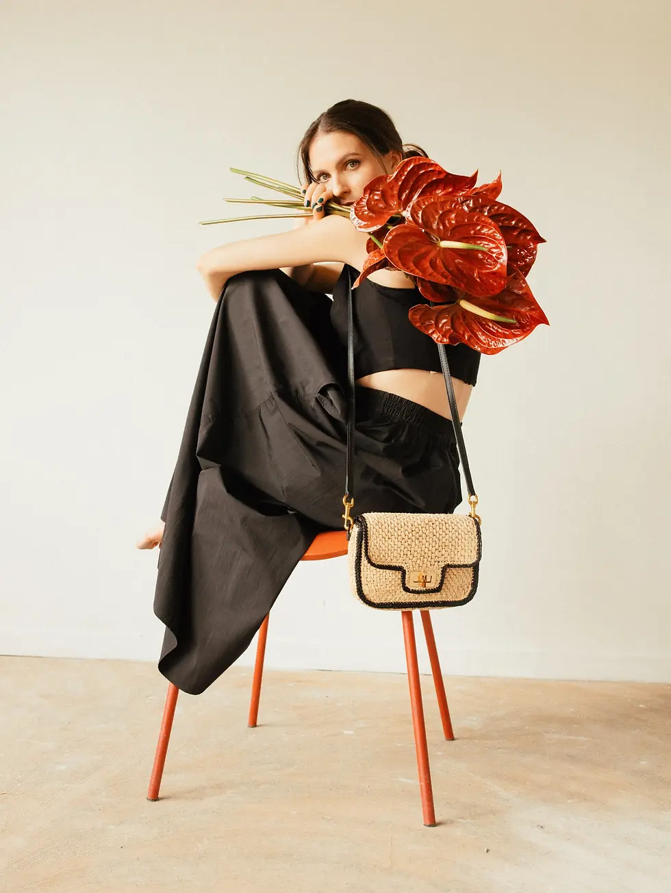 Sac en raphia naturel avec bandoulière noire porté par une femme