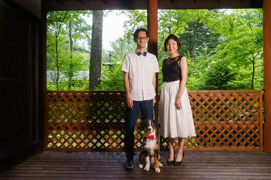 別荘のテラスで愛犬と一緒に立つ新郎新婦、カジュアルなスタイルの記念写真