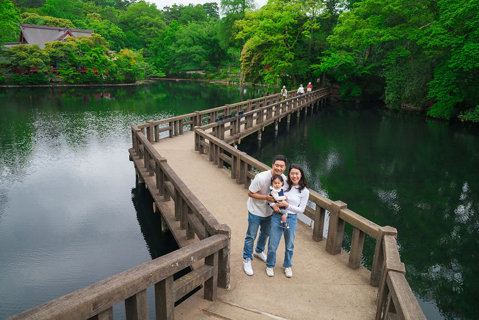 井の頭恩賜公園の池に架かる木橋で微笑む家族。水面に映る新緑と静かな風景が広がる吉祥寺のロケーションフォト。