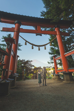 Couple walking through the torii gate of Arakura Sengen Shrine with Mt. Fuji visible in the distance