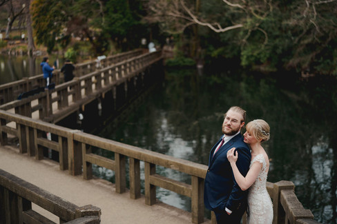 井の頭公園の橋の上で寄り添う新郎新婦のアニバーサリーフォト・湖とボートが広がる風景