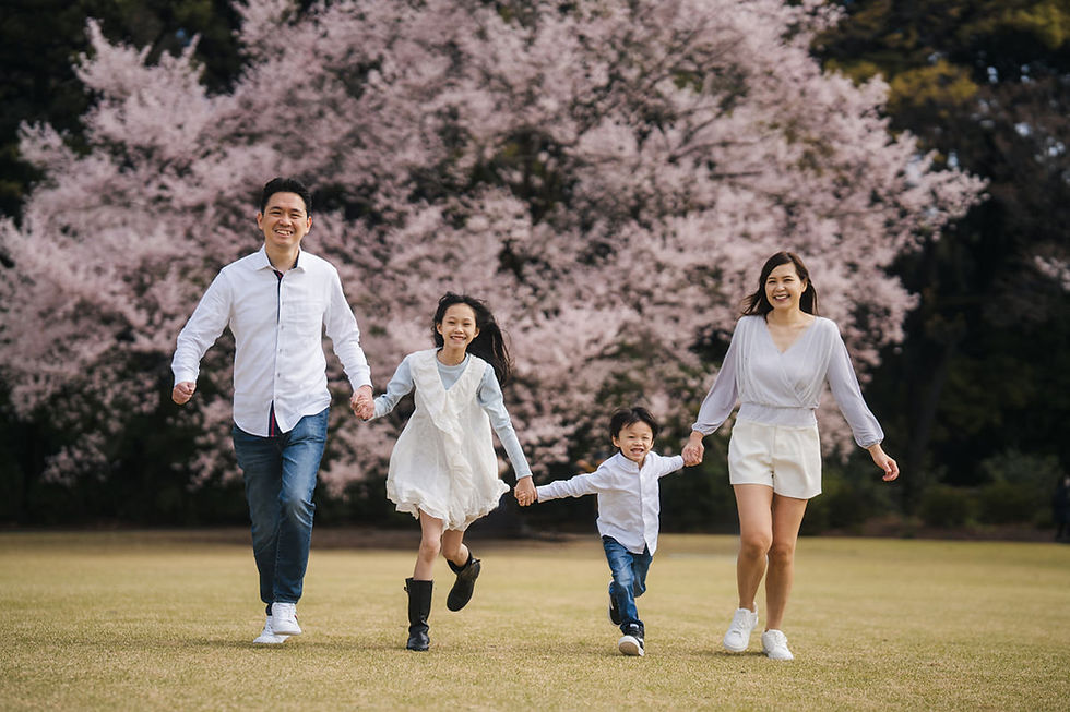 Children running toward their parents during a cherry blossom family photoshoot at Shinjuku Gyoen in Tokyo