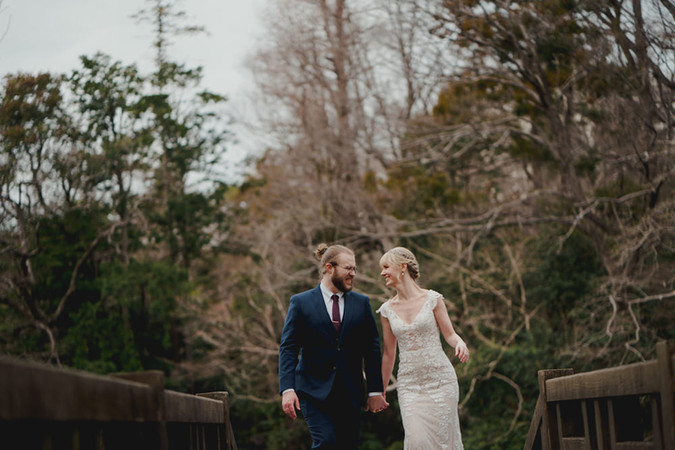 木立の中の橋を手をつないで歩く新郎新婦・自然な雰囲気のロケーション前撮り撮影