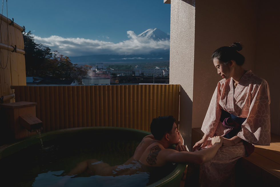 Bride in yukata sitting by her husband who relaxes in a private hot spring bath, with Mount Fuji beautifully framed in the background at Lake Kawaguchiko.