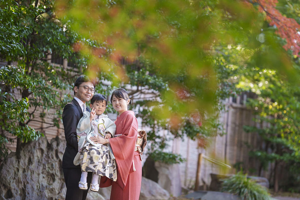 靖国神社の庭園で七五三撮影をする家族 紅葉越しの5歳男の子と両親の写真