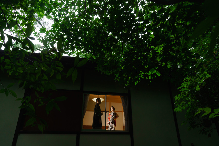 緑に囲まれた軽井沢の別荘、窓辺に立つ和装姿の新郎新婦