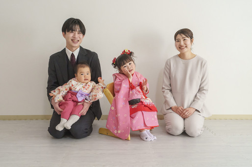 七五三の自宅撮影での家族写真。姉妹と両親が並び、落ち着いた雰囲気で撮影された一枚。