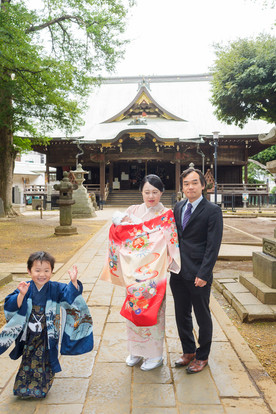     鬼子母神本殿前を駆け寄る5歳男の子とお宮参りの家族