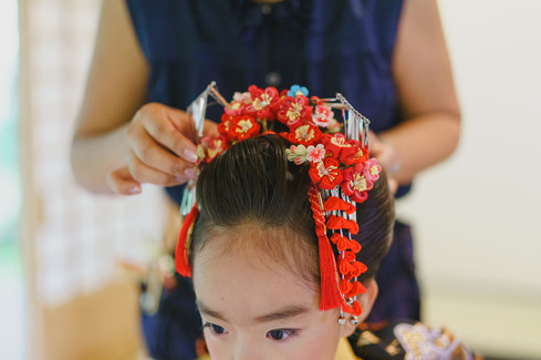 七五三の日本髪に赤い髪飾りをつけるヘアメイクの様子