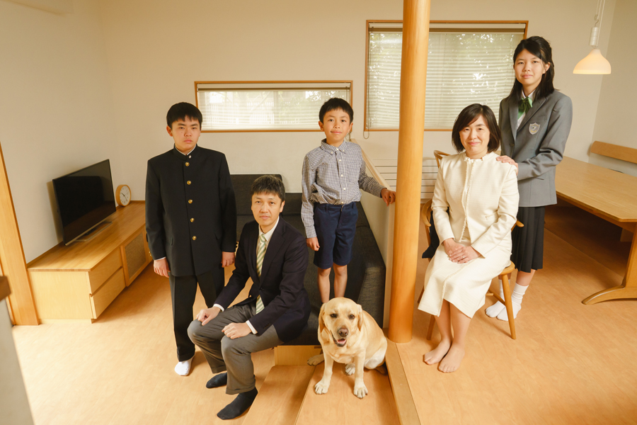 自宅リビングで撮影した家族写真。高校入学・中学入学を迎えた兄妹と両親、弟、そして愛犬がそろって笑顔を見せる