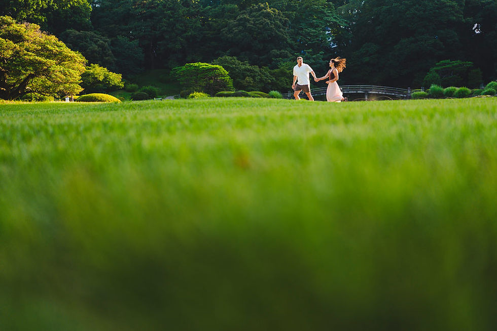 Newly engaged couple running through the gardens at Shinjuku Gyoen during sunset