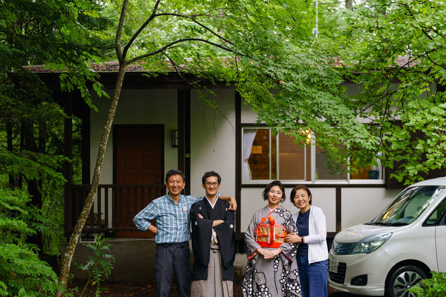 軽井沢の別荘前で家族と並ぶ和装新郎新婦、記念撮影の一枚