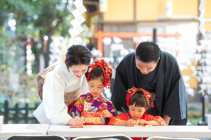 田無神社で絵馬に願い事を書く七五三の姉妹と着物姿の両親