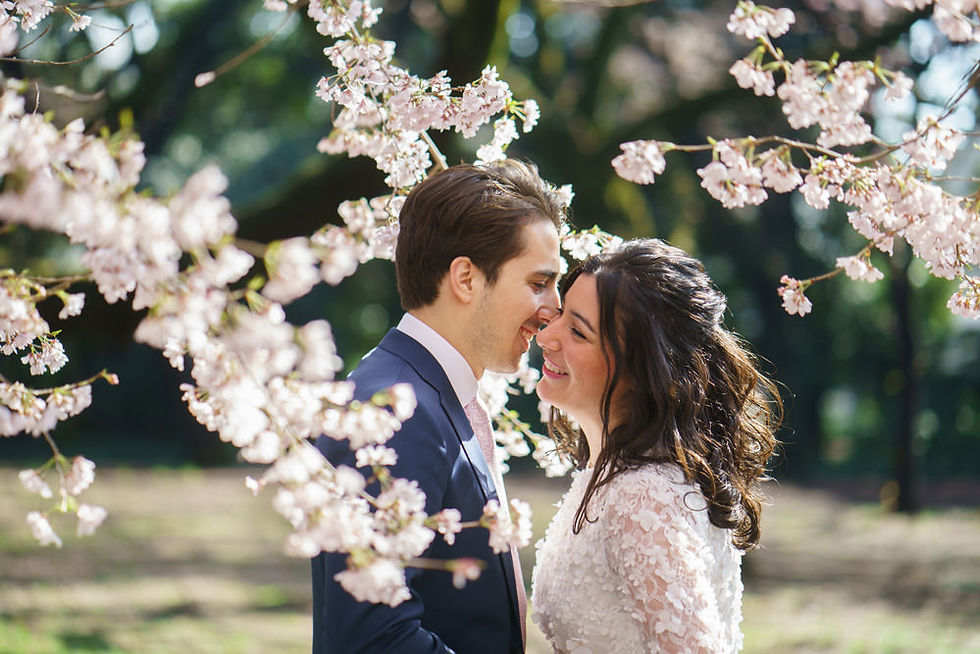Romantic close-up of a couple smiling under pink sakura blossoms in Tokyo during cherry blossom wedding photos in Japan