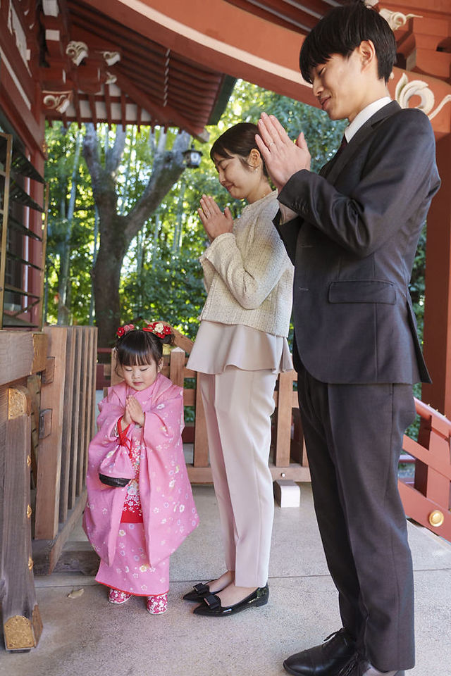 七五三詣りのご祈願中、拝殿で手を合わせる3歳女の子の自然な仕草。