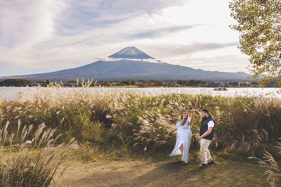 Wide view of an engagement photoshoot at Lake Kawaguchiko, couple walking together with Mt. Fuji and autumn scenery