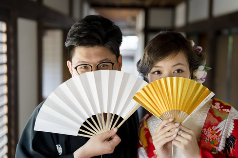 Bride and groom holding folding fans during a kimono pre-wedding photoshoot at Honmaru Goten