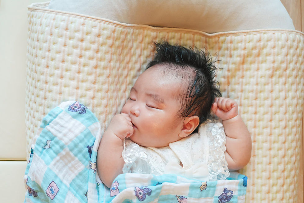 新生児が布団の上で安心した表情で眠っている様子。赤ちゃんの自然な寝顔と柔らかな光が印象的。