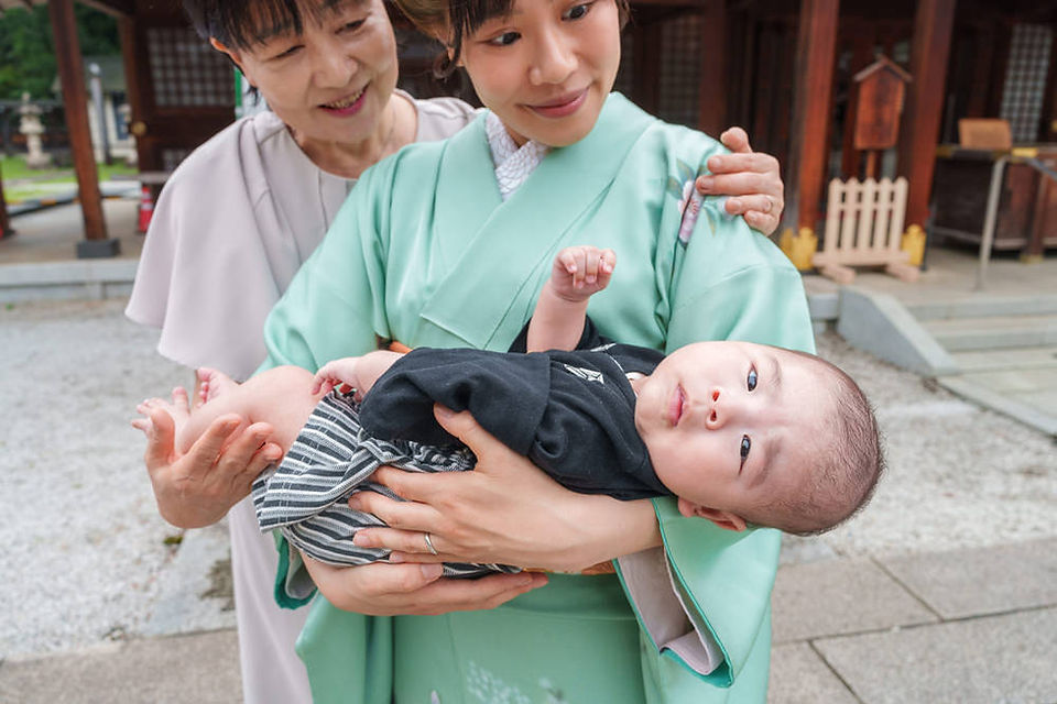 母親と祖母に見守られる赤ちゃんの表情を捉えたお宮参り写真