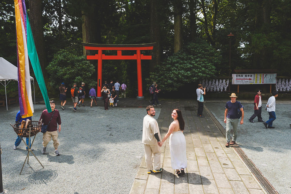 Couple holding hands in the courtyard of Hakone Shrine after their proposal