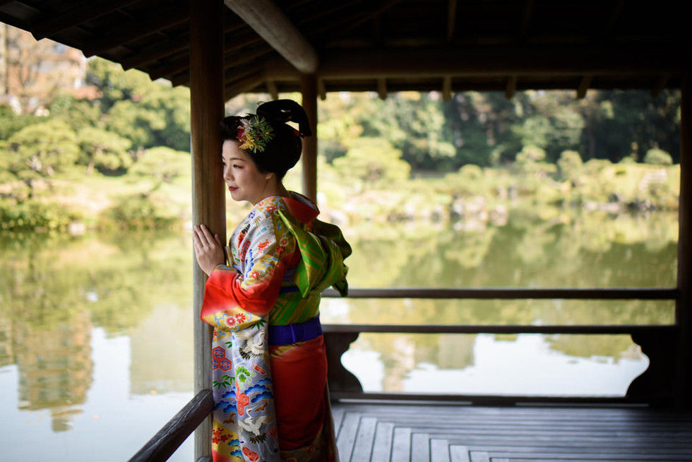 池を望む縁側に立つ花嫁。地毛結い日本髪と色打掛が、静かな庭園の景色と調和し、和装前撮りの美しさを表現。