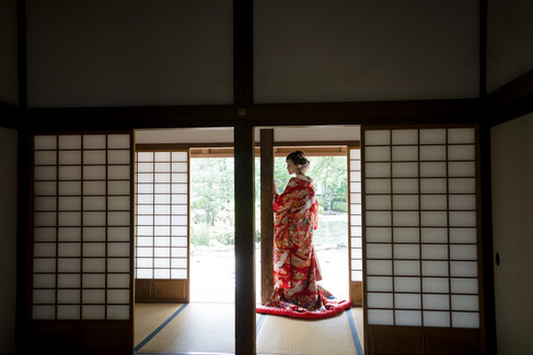 Bride in a colorful Japanese wedding kimono framed by shoji screens at Honmaru Goten