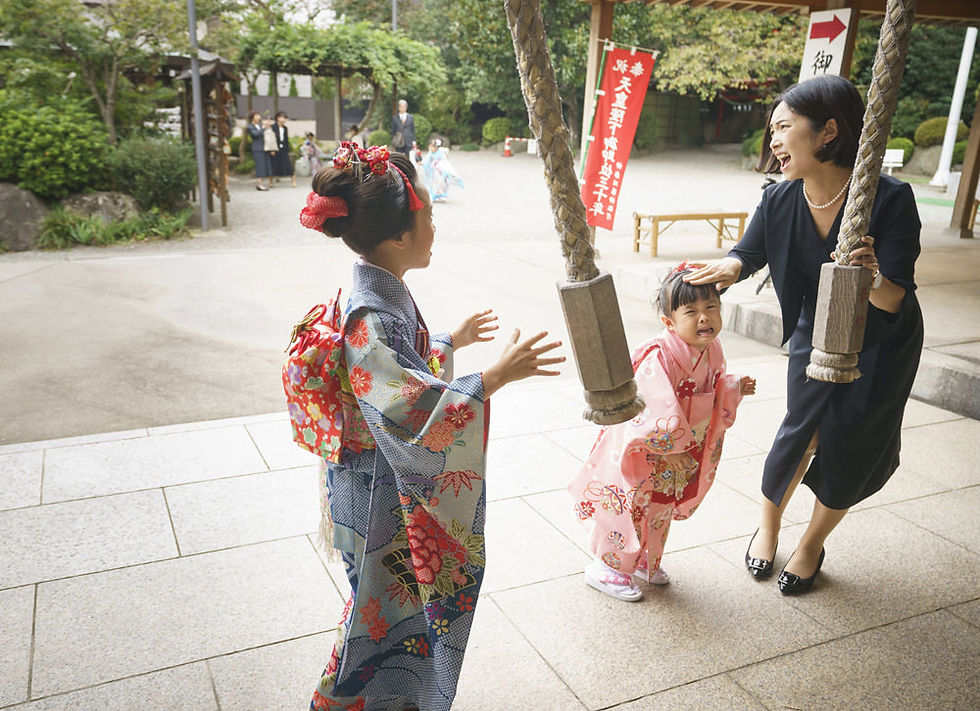 七五三の神社で、泣いてしまった妹をお母さんが優しくなだめる様子と、そばで見守るお姉ちゃんの姿