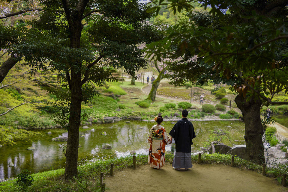 庭園の池を眺める新郎新婦、色打掛と黒紋付姿で自然に溶け込む和装前撮り