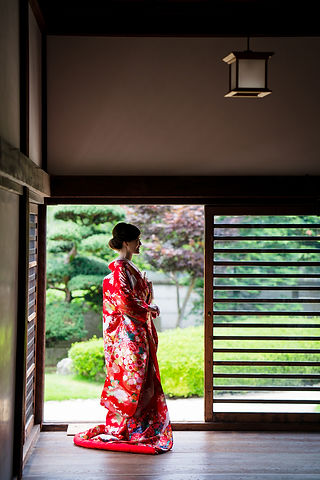 本丸御殿の縁側に立ち、赤い色打掛をまとった花嫁が横顔を見せる姿