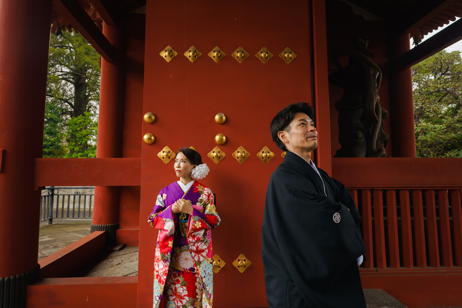 増上寺の赤い門の前で、新婦と新郎が並んで立つ和装ポートレート