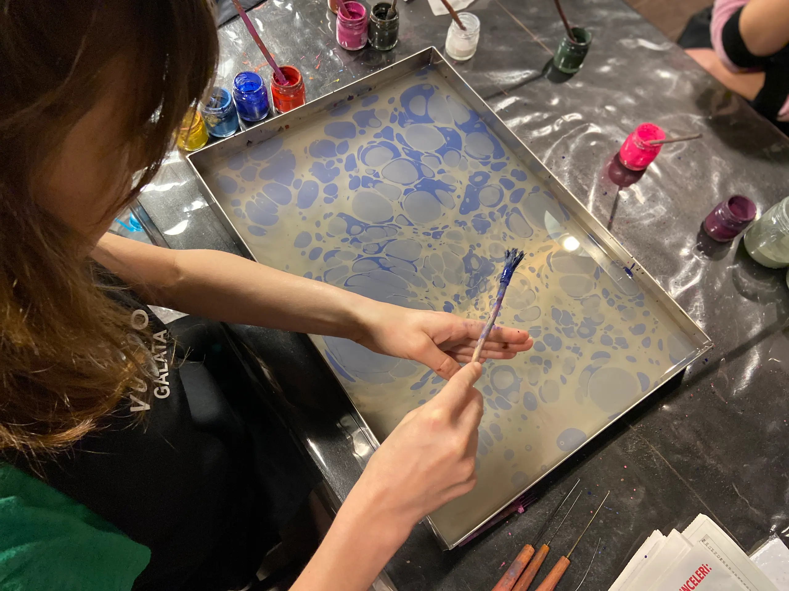 Hands creating marbled paper with comb