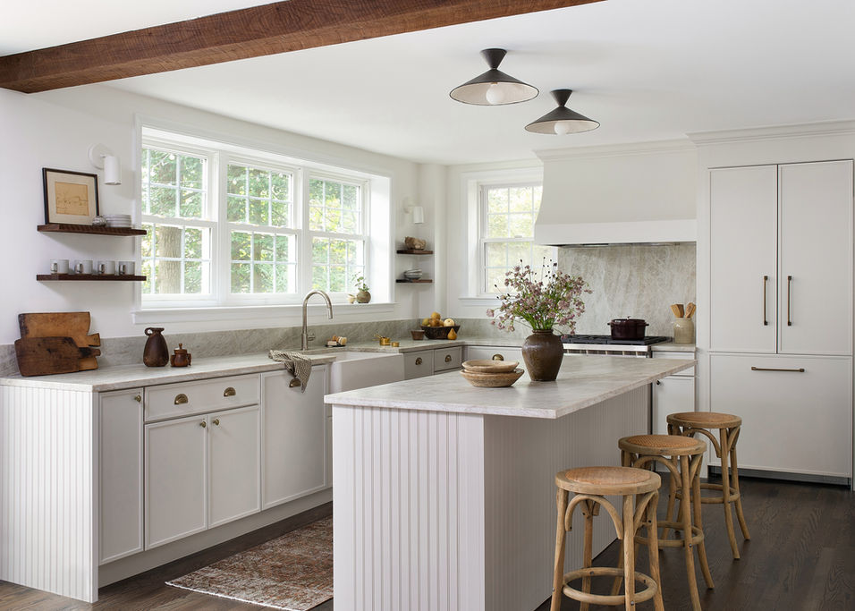 Contemporary kitchen design with light rustic elements, marble countertops and white cabinets.
