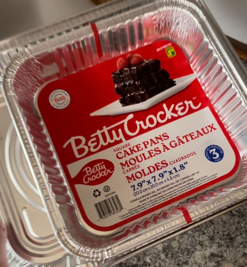 Betty Crocker 3-pack square cake pans with a red label featuring a chocolate cake image. Visible text includes dimensions in inches.