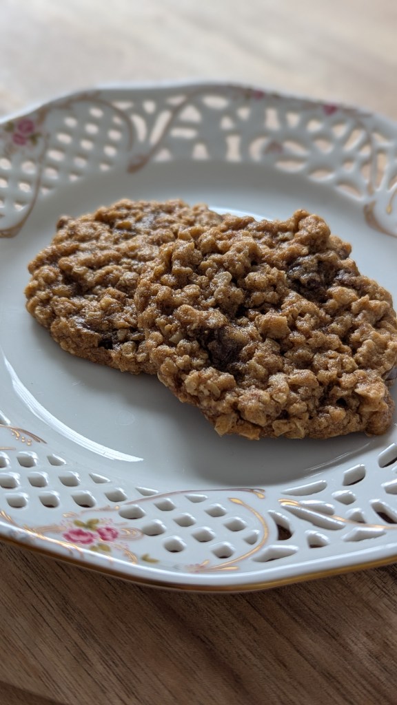 Oatmeal cookies on a decorative white plate with floral patterns, placed on a wooden table. Warm and inviting.