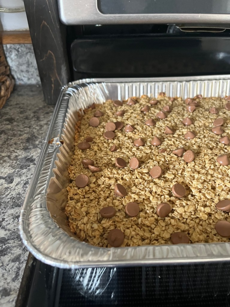 Baked Oatmeal with chocolate chips in a metal tray on a kitchen countertop, near a stove. The setting is cozy and homey.