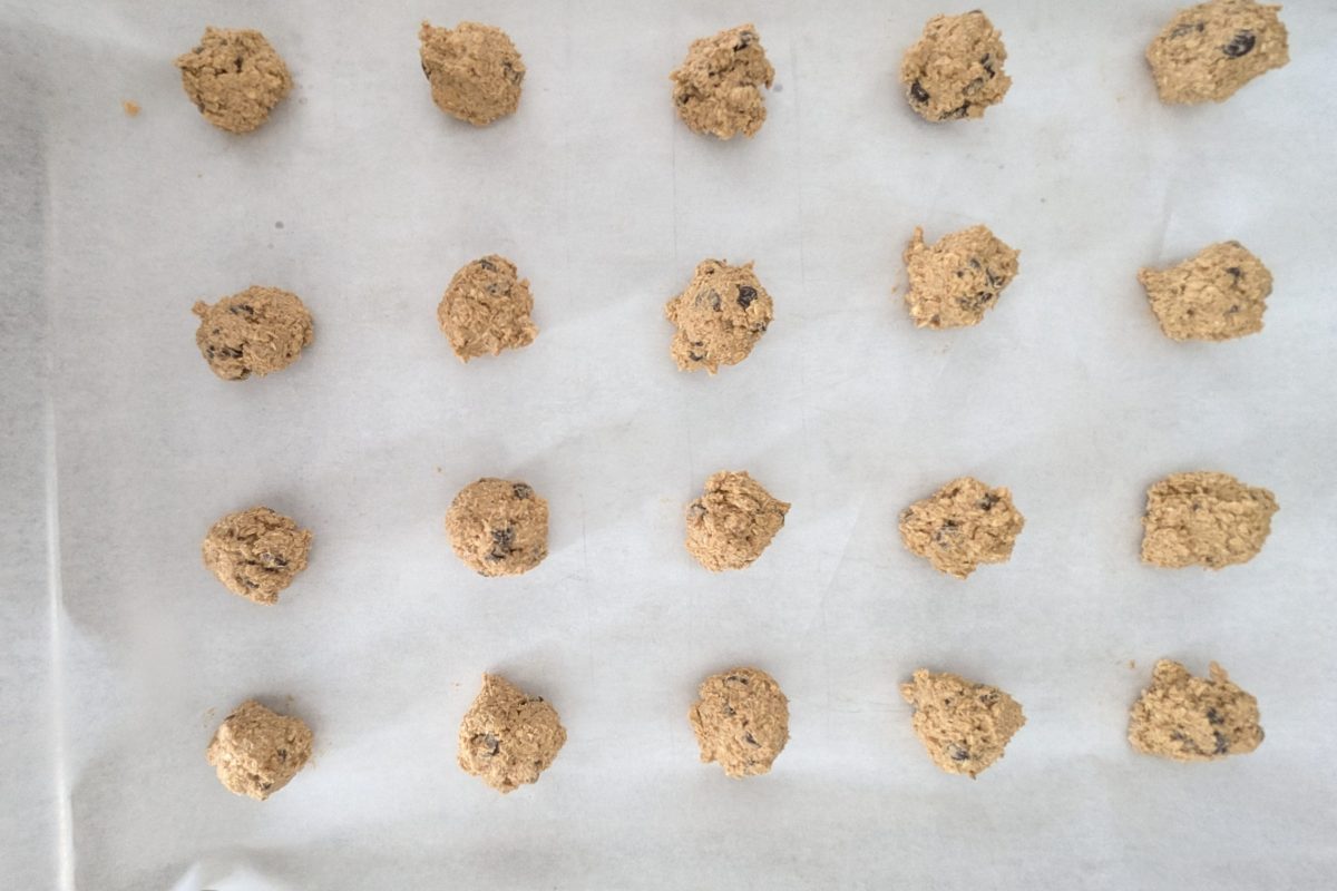 Cookie dough balls on a baking sheet lined with parchment paper, arranged in a grid pattern, ready for baking.