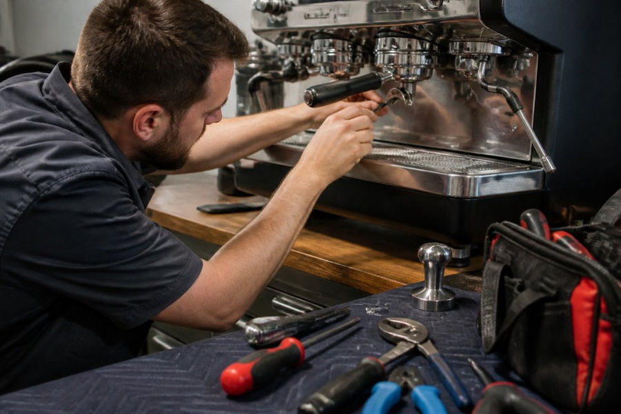 Technician inspecting an espresso machine group head to improve espresso machine repair response time.