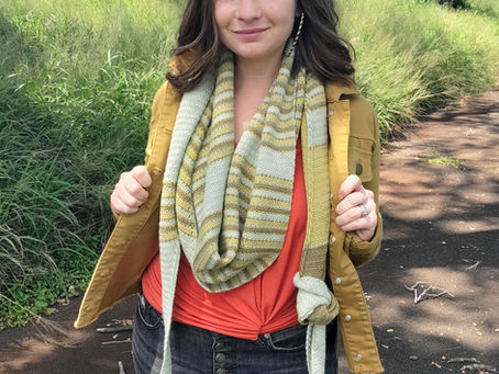 Woman wearing a long, striped green crochet shawl wrapped around her neck with a knot tied in one end.