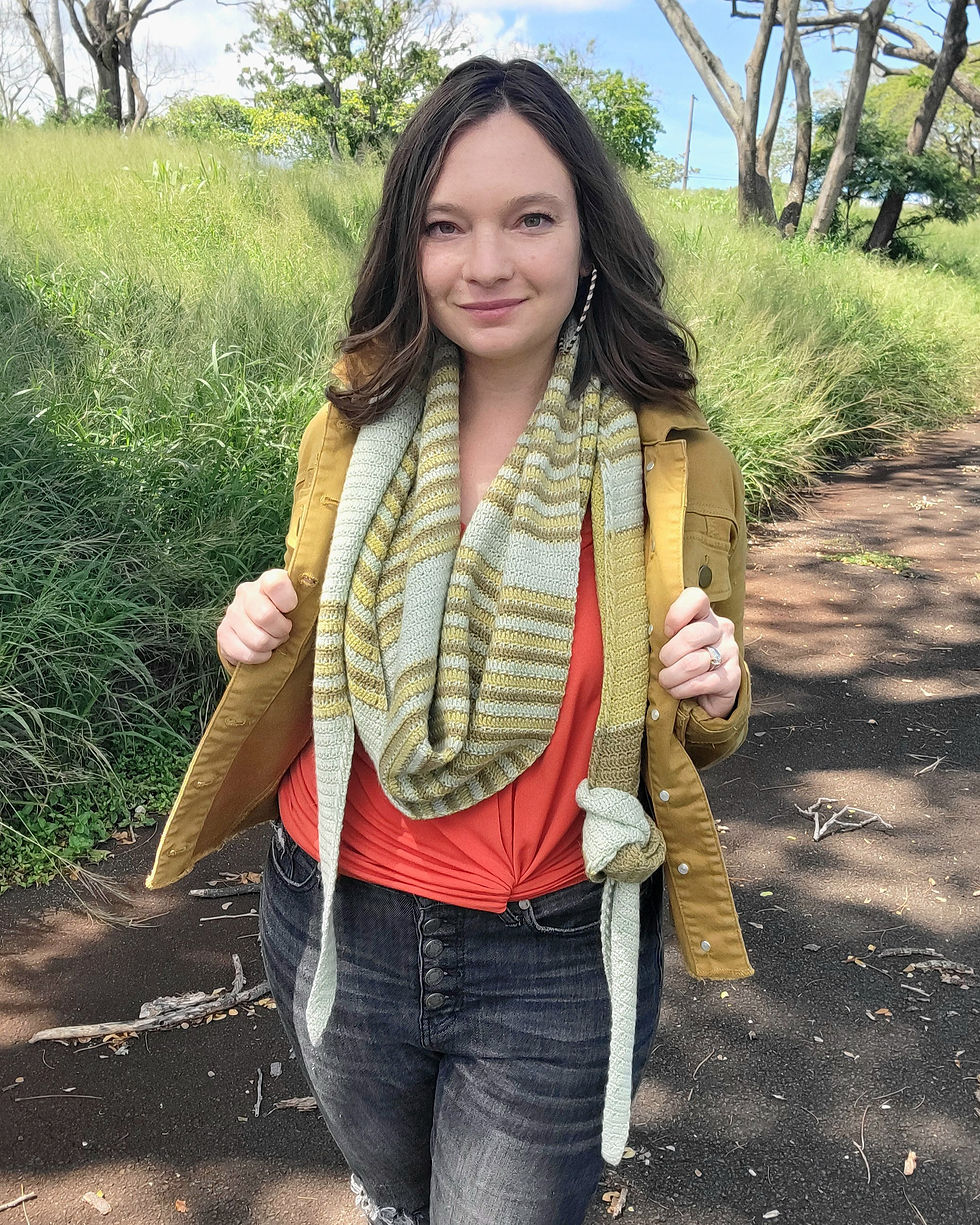 Woman wearing a long, striped green crochet shawl wrapped around her neck with a knot tied in one end.